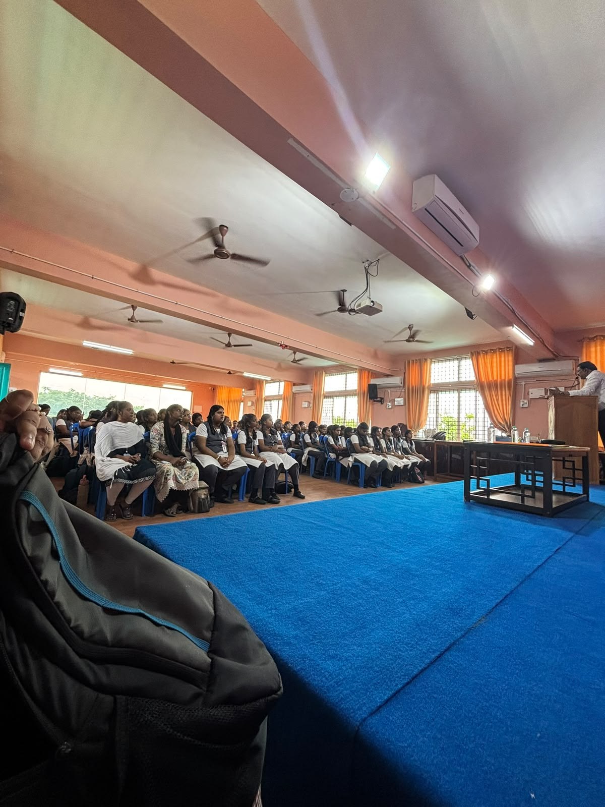 A large student audience seated in a hall during a workshop